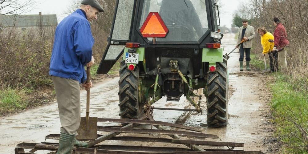 Ta prowizoryczna równiarka pomaga mieszkańcom wsi utrzymać drogę. Od lewej Zdzisław Ruszuk. Fot. J. Mazurek - fot. 