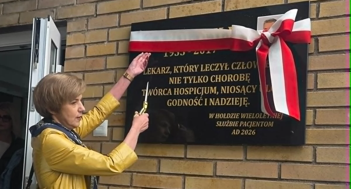 Lekarz Hanna Wilk-Manowiec przy tablicy upamiętniającej jej tatę, doktora Karola Wilka. 