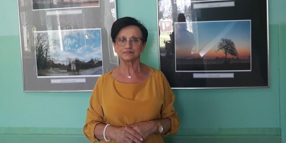 Dyrektor GOK w Repkach Ewa Czarkowska na tle fotografii Heleny Romańskiej.