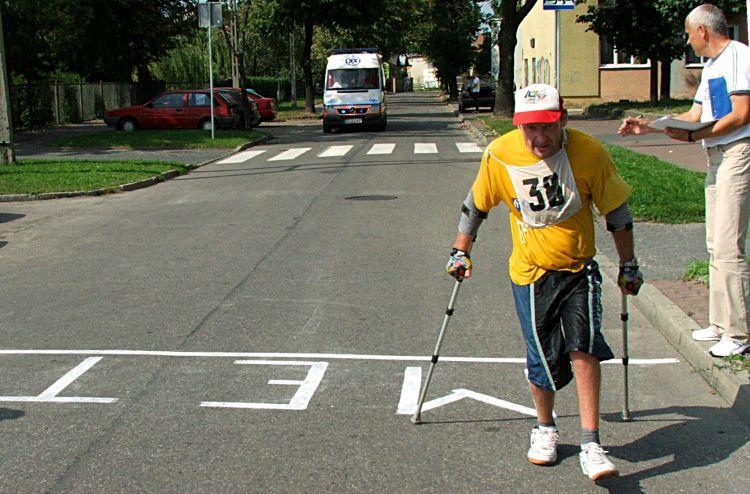 Niepełnosprawny biegacz, Robert Pasko, przekracza linię mety. Dystans 10 km pokonał o kulach. Fot. PGL - fot. 