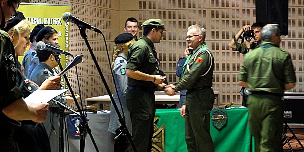 Naczelnik ZHR, hm. Sebastian Grochala wyróżnia phm. Piotra Giczelę za lata służby harcerskiej. Druhowie, skautowym zwyczajem ściskają sobie lewą rękę. Tradycja ta wynika z podkreślenia serdeczności i skautowego braterstwa. Fot. M. Giczela - fot. 