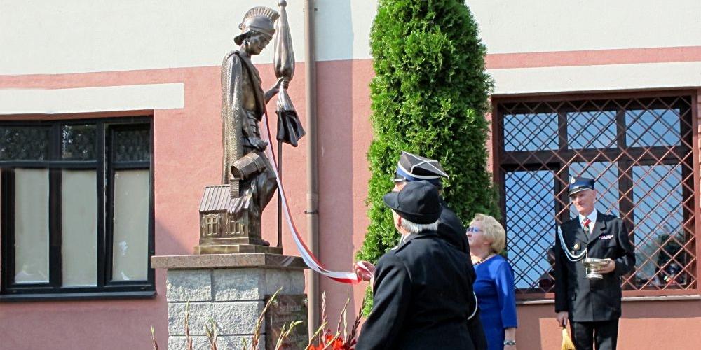 Figurę św. Floriana odsłaniają: (od lewej) Barbara Rosa, Janusz Kozioł i Hanna Stosio. Fot. PGL