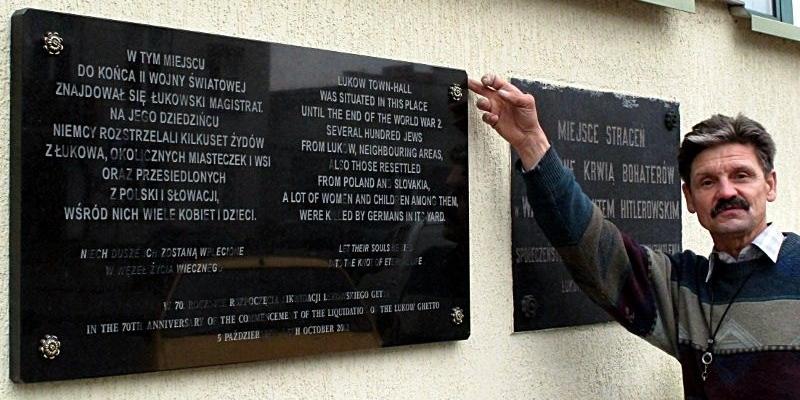 Przedstawiciel firmy kamieniarskiej montującej pamiątkową tablicę na ścianie gmachu PKO i PZU, prezentuje nowe miejsce pamięci. Fot. PGL - fot. 