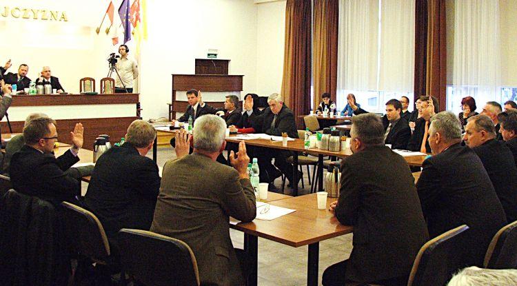 Radni głosują uchwałę o stwierdzeniu wygaśnięcia mandatu. Ci, którzy trzymają rękę w górze, są przeciw. Radny Z. Gajda siedzi tyłem przy rogu stołu z podniesioną ręką. Fot. PGL - fot. 